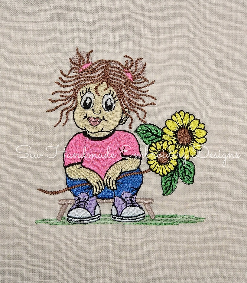 Adorable little girl sittiing down nursing a large sunflower pattern stitched onto linen material in embroidery
