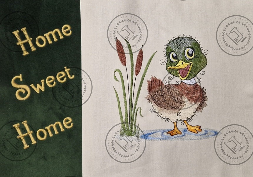 "An embroidered design of a cheerful mallard duck with a vibrant green head, brown and beige body, and yellow beak. The duck is standing in a small blue puddle next to tall cattail reeds, with a whimsical and curly detailing style."